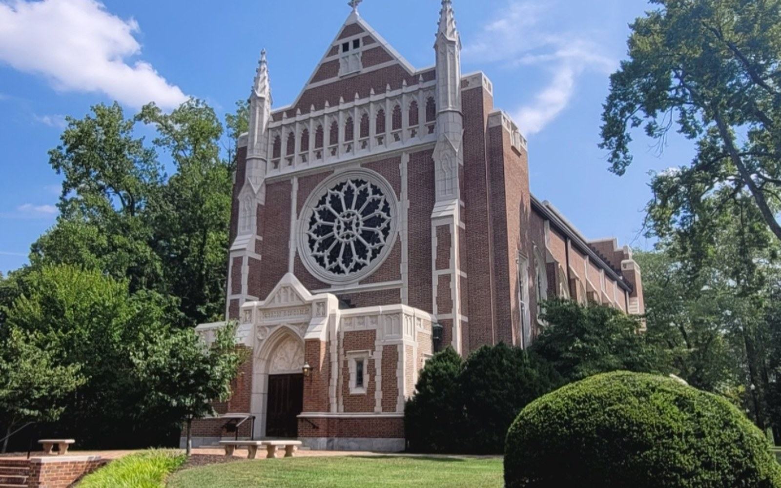 Brick Gothic-style chapel with a stone rose window and pointed spire finials